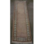 20th Century Nepalese wool runner, pink ground with stylized floral pattern border, W82cm L297cm