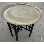 Indian brass table top engraved with stylised motif, on a black Moorish style folding stand D58cm