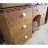Early C20th waxed pine dog kennel type dresser, with seven drawers with ceramic handles around an