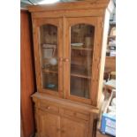 Waxed pine side cabinet, with two glazed doors above a pair of drawers and a pair of arched panel