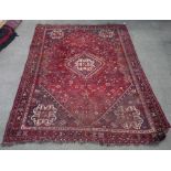 C20th Turkish wool rug with central geometric medallion on red ground surrounded by stylised