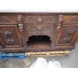 Late Victorian oak side board with two drawers enclosed by a pair of doors, carved with scrolls,