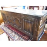 C17th style oak blanket box with hinged lid and carved four panel front W129cm D43cm H49cm