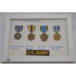 Framed and mounted displays of USA military medals: one with WWII period medals including merit