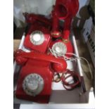 Red candlestick type telephone and two other red dial telephones (3)