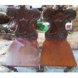 Pair of Regency mahogany hall chairs, scroll carved back with shield shaped cartouche, solid seats