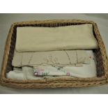 Wicker basket containing a selection of embroidered and lace edged table linen