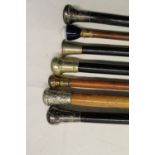 Collection of seven metal topped walking canes with various woods including ebony, bamboo, etc