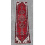 A Hamadan woollen hand-made runner with red ground, 110 by 29ins. (280 by 74cms.).
