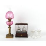 Property of a lady - a brass paraffin oil lamp with cranberry glass reservoir & shade; together with