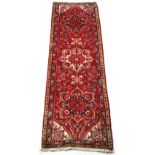 An Arazi woollen hand-made runner, with red ground, 96 by 30ins. (244 by 76cms.).
