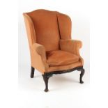 Property of a deceased estate - an early 20th century upholstered wing armchair with carved cabriole