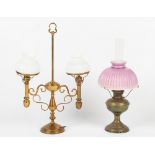 A brass paraffin oil lamp with pink glass shade; together with a brass twin light table lamp (2).
