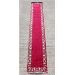 A Tabriz woollen hand-made runner, with burgundy ground, 189 by 33ins. (480 by 84cms.).