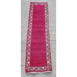 A Tabriz woollen hand-made runner, with burgundy ground, 124 by 33ins. (315 by 84cms.).