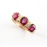 An unmarked yellow gold ruby & diamond ring, the three oval cushion cut rubies alternating with