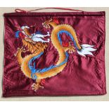 An embroidered silk wall hanging depicting a dragon on a burgundy ground, 26 by 31ins. (66 by 78cms.