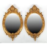 Property of a gentleman - a pair of Victorian gilt framed oval wall mirrors with bevelled glass