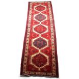 An Arazi woollen hand-made runner, with red ground, 134 by 47ins. (340 by 107cms.).