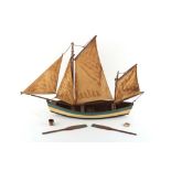 A painted wood model fishing boat, complete with two oars, a folded net, a lobster pot, and a