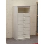A modern white painted narrow chest of seven drawers.