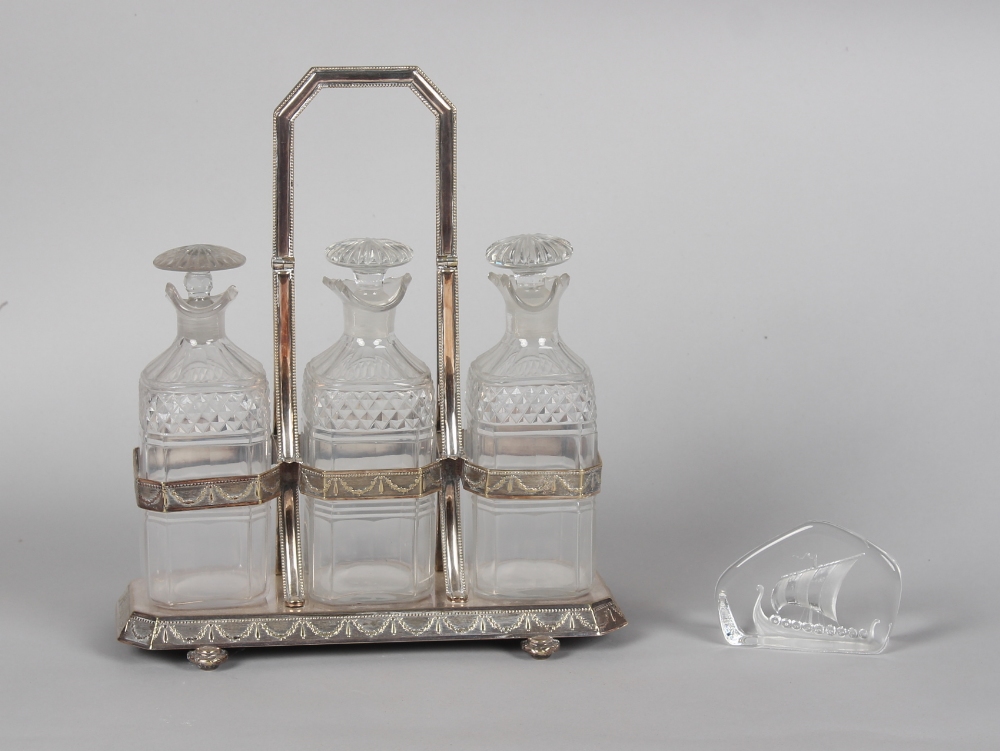 An Edwardian silver plated three bottle tantalus; together with a Mats Jonasson, Sweden glass