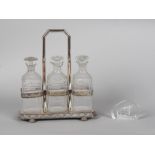 An Edwardian silver plated three bottle tantalus; together with a Mats Jonasson, Sweden glass