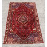 A modern Persian hand-knotted wool rug with red ground, 113 by 77ins. (287 by 196cms.).
