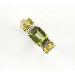 An Art Deco style 9ct yellow gold ring set with three emerald cut peridots alternating with rows