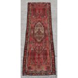 A Hamadan hand knotted wool runner with red ground, 115 by 36ins. (292 by 91cms.).