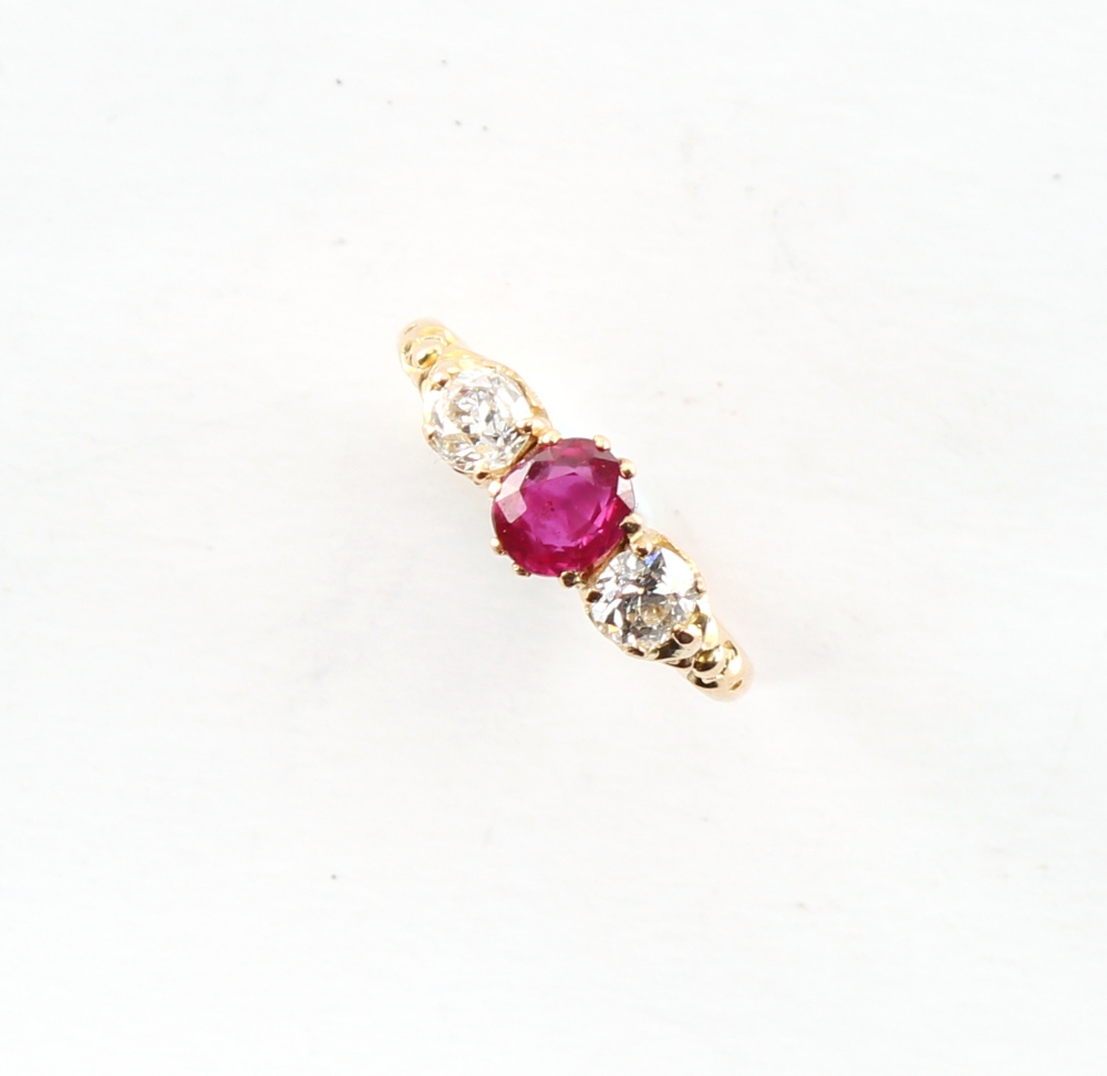 An Edwardian 18ct yellow gold ruby & diamond three stone ring, the centre oval cushion cut ruby