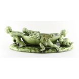 A Clement Massier green glazed centrepiece modelled as four putti hauling a rowing boat,