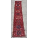 An Azari woollen hand-made runner with red ground, 162 by 32ins. (410 by 81cms.).