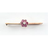 An unmarked gold ruby flowerhead bar brooch, the pin cracked, 52mm long, in associated box.