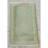 An Art Deco style hand knotted wool rug with green ground, 58 by 36ins. (147 by 91cms.).