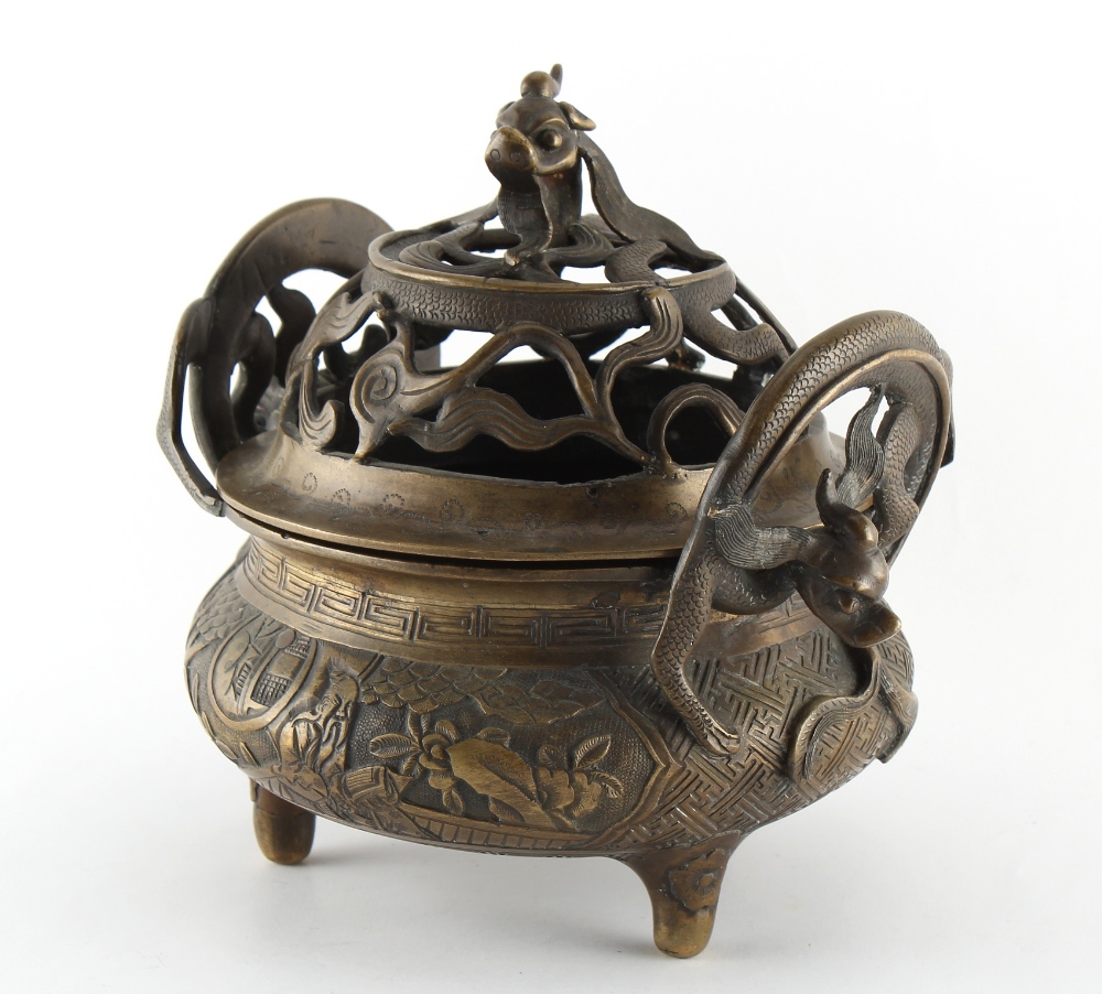 A Chinese ornate bronze censer, the pierced cover with dragon finial, 8.7ins. (22cms.) across (