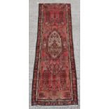 A Hamadan hand knotted wool runner with red ground, 115 by 36ins. (292 by 91cms.).