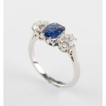 An 18ct white gold & platinum sapphire & diamond three stone ring, the cushion cut sapphire of