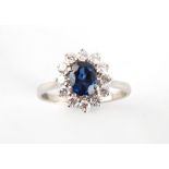 An 18ct white gold sapphire & diamond oval cluster ring, the oval cushion cut sapphire of good