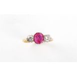 An 18ct yellow gold & platinum ruby & diamond three stone ring, the oval cushion cut ruby