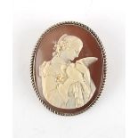 A well carved shell cameo brooch depicting Aphrodite holding a dove, in unmarked white metal (