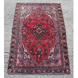 A Hamadan woollen hand-made rug with red ground, 106 by 71ins. (270 by 180cms.).