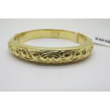 A Modern Bangle, allover detailed in relief, hinged to snap clasp, stamped "750" (internal