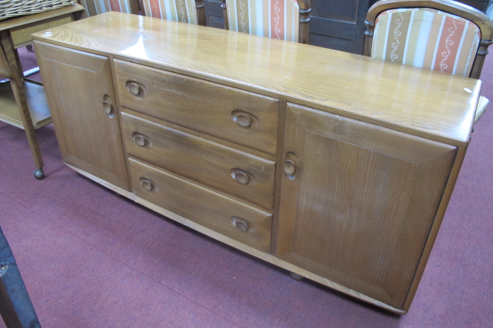 Ercol Blonde Sideboard, with oval handles to three drawers and flanking cupboard doors, on