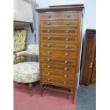 An Edwardian Mahogany Chest of Drawers, with a low back, cross banded top, ten cross banded drawers,