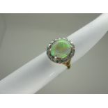 An Opal and Diamond Cluster Ring, the high oval cabochon opal (chipped) claw set, within claw set