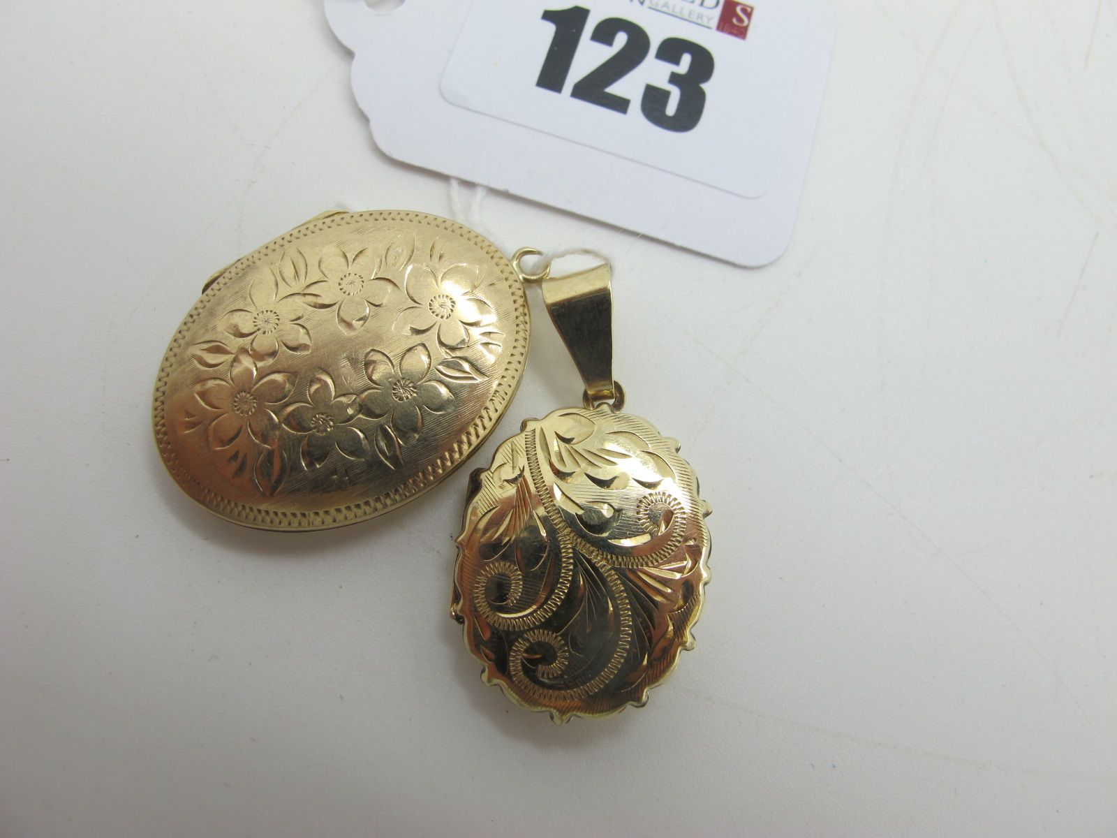 An Oval Locket Pendant, leaf scroll engraved, stamped "375"; together with a 9ct gold locket