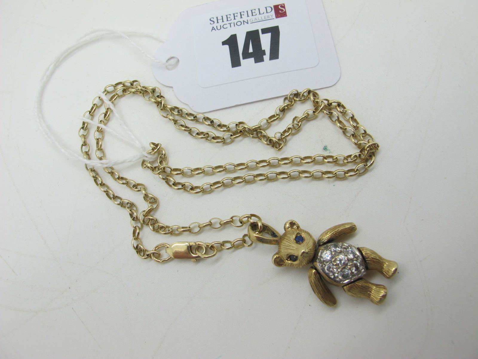 A 9ct Gold Articulated Teddy Bear Pendant, with inset highlights, on a 9ct gold belcher link chain.