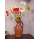 A Large Stoneware Jug, with faux flowers, 52.5 cm high.