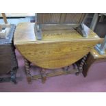 A 1930's Oak Drop Leaf Table, with oval top, on barley twist supports.